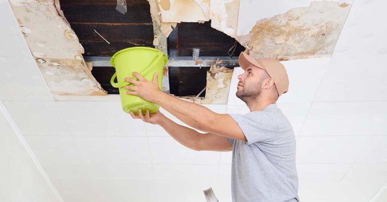 every business should have an emergency fund; photo of man standing on water collecting water falling from the ceiling