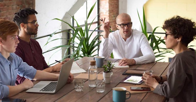 honor credit union has three tips to reduce business costs; photo of employees sitting at a table talking