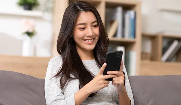 woman sitting on a couch looking at a mobile phone